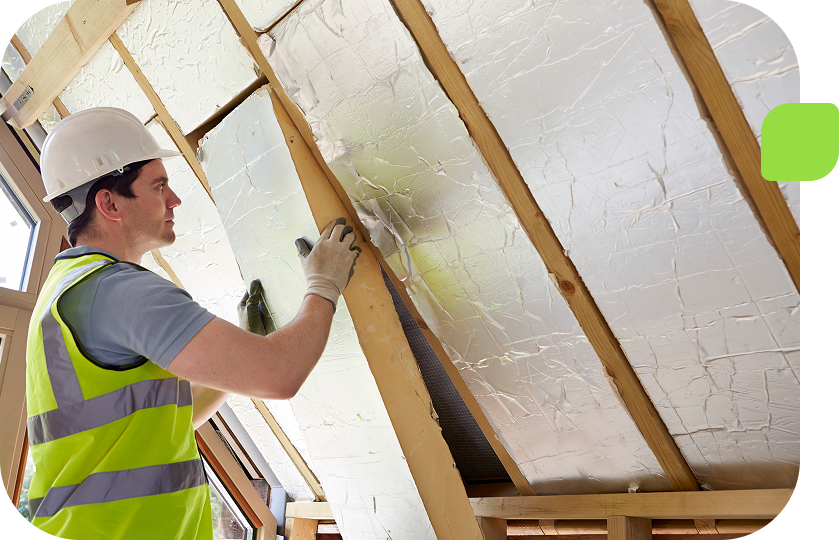 Worker installing insulation in attic space.